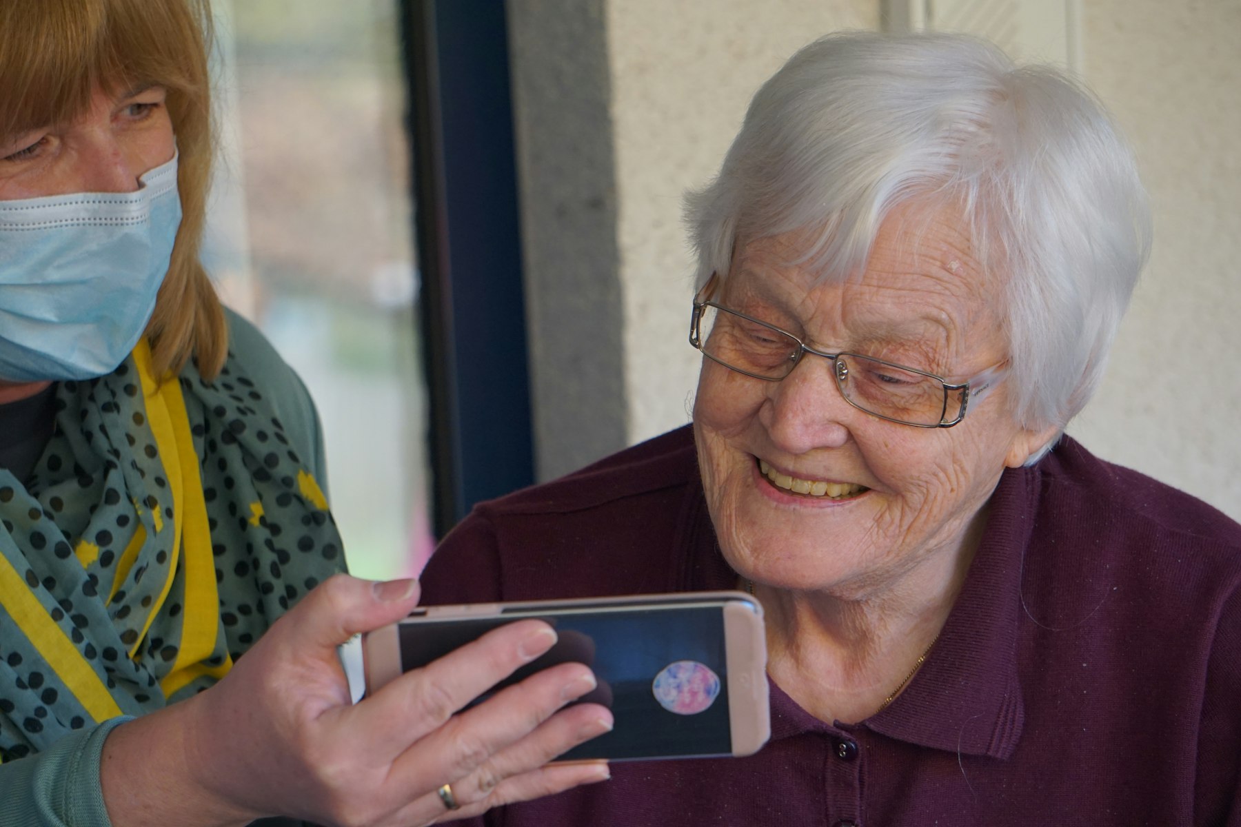 Home health caregiver showing a patient a smartphone